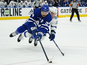 Toronto Maple Leafs forward Auston Matthews (34) battles with Tampa Bay Lightning forward Ondrej Palat (18) for the puck at Scotiabank Arena.