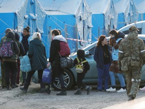 Civilians evacuated from the Azovstal steel plant in Mariupol walk accompanied by a member of the International Committee of the Red Cross and a UN staff member, as they arrive at a temporary accommodation center in the village of Bezimenne, during the Ukraine-Russia conflict in Donetsk region, Ukraine, Friday, May 6, 2022.