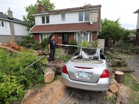 An Ottawa resident looks over her destroyed car and damaged home on May 26, 2022 after a storm hit the region on May 21.