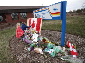 Children sign a Canadian flag at an impromptu memorial in front of the RCMP detachment April 20, 2020 in Enfield, Nova Scotia.