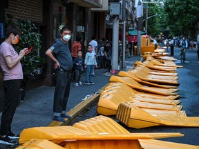 People stand next to barriers in the Jing' an district of Shanghai on May 31, 2022, as the city prepares to lift more curbs after two months of heavy-handed restrictions.