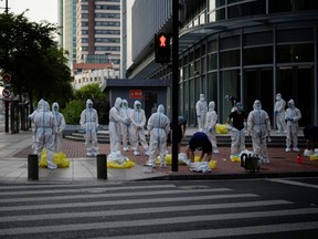 Workers in protective suits gather at a street during lockdown, amid the COVID-19 outbreak, in Shanghai, China, Wednesday, May 25, 2022.