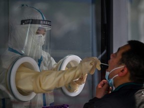 A health worker takes a swab sample from a man during a COVID-19 lockdown in the Jing'an district in Shanghai, China, Friday, May 27, 2022.