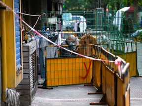 A resident checks his phone behind the barriers of a locked down area during the lockdown in Shanghai, China, on May 16, 2022.