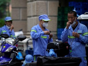 Workers take rapid antigen tests for COVID-19 on a street during lockdown, amid the COVID-19 pandemic, in Shanghai, China, Friday, May 20, 2022.