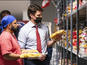 Prime Minister Justin Trudeau looks at some of the food that will be given away during a visit to the Guru Nanak Food Bank in Surrey, B.C. on Tuesday May 24, 2022.