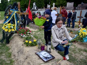 Die Menschen zollen neben den Gräbern auf dem Lychakiv-Friedhof Respekt, wo Menschen, die bei der russischen Invasion in der Ukraine getötet wurden, begraben werden, während der Tag der Helden der himmlischen Hundert gefeiert wird, in Lemberg, Ukraine, am 22. Mai 2022.