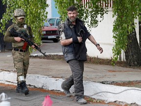 A wounded service member of Ukrainian forces who had surrendered after weeks holed up at Azovstal steel works is escorted by a member of the pro-Russian military at a detention facility in the course of Ukraine-Russia conflict in the settlement of Olenivka in the Donetsk Region, Ukraine May 17, 2022.