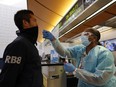 Scott Fujii is given a 24-hour rapid coronavirus test by nurse Caren Williams at Tom Bradley international terminal at LAX airport so he can travel to Hawaii to see family, in Los Angeles, Nov. 23, 2020.