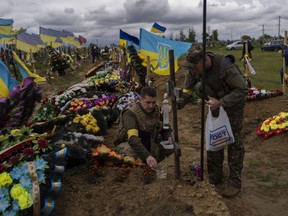 Two national guards visit the grave of a late soldier in Kharkiv cemetery, eastern Ukraine, Sunday, May 22, 2022.