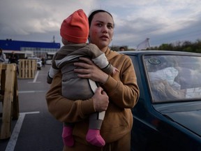 A woman reacts as she holds a child after arriving from a Russian-occupied territory at a registration and processing area for internally displaced people in Zaporizhzhia, Ukraine, Monday, May 2, 2022.