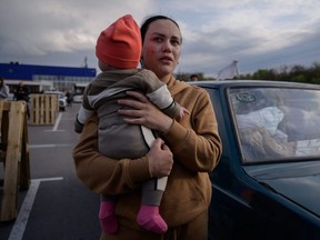 A woman reacts as she holds a child after arriving from a Russian-occupied territory at a registration and processing area for internally displaced people in Zaporizhzhia, Ukraine, Monday, May 2, 2022.