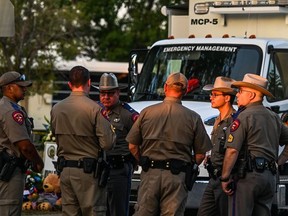 Police officers speak near a makeshift memorial for victims of the shooting outside Robb Elementary School in Uvalde, Texas, May 27, 2022.
