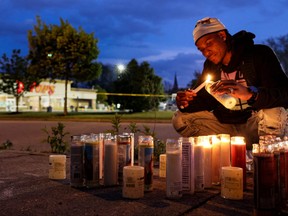 A man lights a candle at a memorial for victims at the scene of a shooting at a Tops supermarket in Buffalo, N.Y., May 16, 2022.