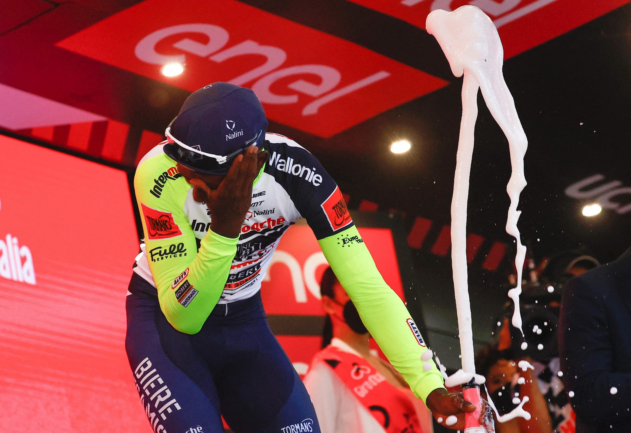 Eritrean rider Biniam Girmay Hailu reacts after popping a champagne cork as he celebrates on the podium after winning the 10th stage of the Giro d'Italia 2022 cycling race. 