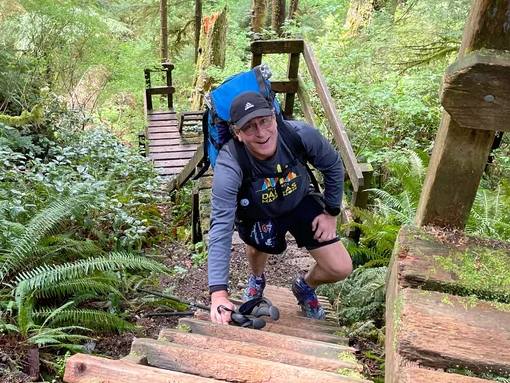 Man hiking up wooden staircase on hiking trail.
