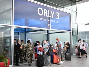 In this file photo taken on Aug. 1, 2020, travellers, wearing protective face masks, line up at the Orly Airport, south of Paris during a major weekend of the French summer holidays.