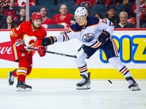 Calgary Flames left wing Johnny Gaudreau and Edmonton Oilers right wing Jesse Puljujarvi battle for the puck during the third period at Scotiabank Saddledome.