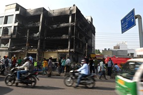Onlookers gather outside a burn down commercial building a day after a fire broke out, in New Delhi on May 14, 2022.