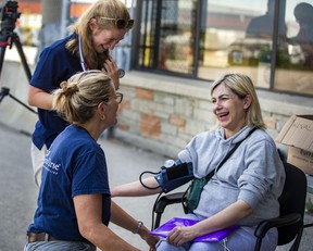 Nataliya Sobetca, who is eight months pregnant and part of a group fleeing war in Ukraine, receives a check-up from volunteer nurses Kim Wiebe (top) and Marcella Veenman-Mulder, after arriving at a terminal in the Toronto Pearson Airport on a plane from Poland, operated by Samaritan's Purse Canada on Sunday, May 15, 2022. ERNEST DOROSZUK/TORONTO SUN