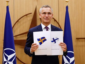NATO Secretary-General Jens Stoltenberg poses with application documents presented by Finland's Ambassador to NATO Klaus Korhonen and Sweden's Ambassador to NATO Axel Wernhoff during a ceremony to mark Sweden's and Finland's application for membership in Brussels, on May 18, 2022.
