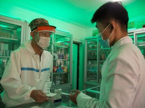 A doctor from the Korean People's Army visits a pharmacy to give a man prescription medicine in Pyongyang on May 27, 2022.