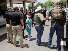 Ein Kind steigt in einen Schulbus, während Polizeibeamte den Schauplatz einer mutmaßlichen Schießerei in der Nähe der Robb Elementary School in Uvalde, Texas, am 24. Mai 2022 bewachen.