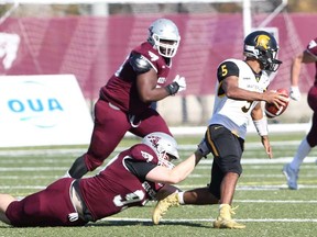 Waterloo Warriors quarterback Tre Ford evades Ottawa Gee-Gees defenders during an Ontario University Athletics football quarterfinal playoff game at uOttawa on Saturday, Oct. 26, 2019.