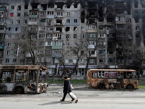 A resident walks along a street past burnt-out buses in the southern port city of Mariupol, Ukraine April 19, 2022.