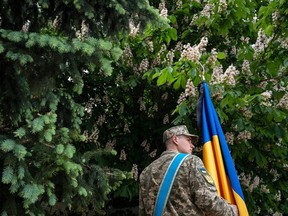 A Ukrainian serviceman holds a Ukrainian flag during a funeral of Eduard Trepylchenko, recently killed in the Kharkiv region in a fight with Russian troops, during Russia's invasion of Ukraine, in Kyiv, Ukraine May 25, 2022.