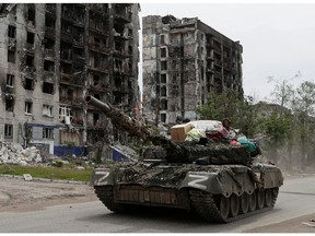 Militärangehörige prorussischer Truppen fahren während des Ukraine-Russland-Konflikts in der Stadt Popasna in der Region Luhansk, Ukraine, am 26. Mai 2022 einen Panzer entlang einer Straße an einem zerstörten Wohnhaus vorbei.