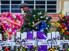 A police officer stands near the makeshift memorial for the shooting victims outside Robb Elementary School in Uvalde, Texas, on May 28, 2022.