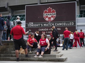 Fans sit and gather outside BC Place stadium after the Canadian national men's soccer team's friendly match against Panama was cancelled due to a labour dispute.