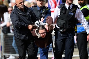 Ein Demonstrant wird mitgerissen, nachdem er die Rückgewinnung des königlichen Landes gefordert hat, indem er auf die Mall stürmt, während eine Militärkapelle die Trooping the Colour-Parade am 2. Juni 2022 in London anführt.  (Foto von Leon Neal/Getty Images)