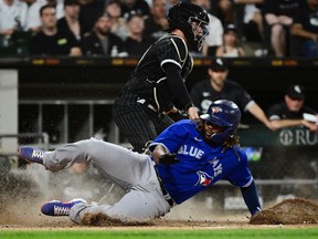 Vladimir Guerrero Jr. #27 of the Toronto Blue Jays slides into home base to score in the sixth inning against Reese McGuire #21 of the Chicago White Sox at Guaranteed Rate Field on June 20, 2022 in Chicago, Illinois.