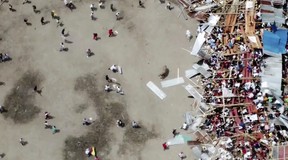 In this image taken from video, a man, centre, attempts to gain the attention of a bull as part of a wooden stand collapses during a bullfight, sending spectators plunging to the ground Sunday, June 26, 2022, at a stadium in the city of El Espinal in Tolima state, central Colombia. (AP Video)