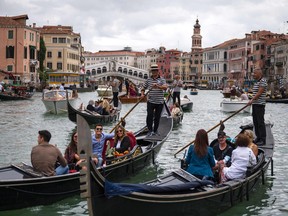 In this file photo taken on Sept. 18, 2021 Tourists enjoy a gondola ride on the Grand Canal by the Rialto bridge in Venice.