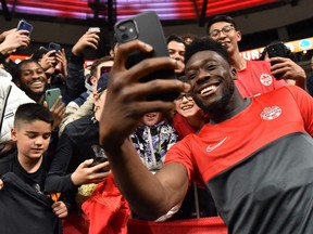 Canada's midfielder Alphonso Davies (R) signs autographs and takes photos with fans following the Concacaf Nations League football match between Canada and Curacao at BC Place stadium in Vancouver on June 9, 2022.
