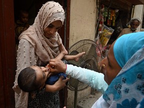 A health worker administers polio vaccine drops to a child during a door-to-door polio vaccination campaign at a slum area in Lahore on June 27, 2022.