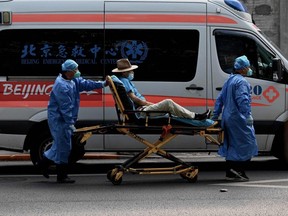 Health workers carry a man on a stretcher to a fever clinic in Beijing, Tuesday, June 14, 2022.