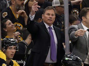 Boston Bruins head coach Bruce Cassidy, centre, gestures during the third period of an NHL hockey game against the Pittsburgh Penguins, April 16, 2022, in Boston.