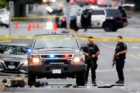 Polizisten versammeln sich, nachdem zwei bewaffnete Männer, die eine Bank betraten, bei einer Schießerei mit der Polizei in Saanich, BC, am 28. Juni 2022 getötet wurden.