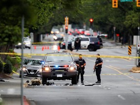 Police officers gather after two armed men entering a bank were killed in a shootout with the police in Saanich, British Columbia, June 28, 2022.
