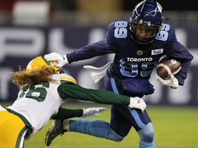 Toronto Argonauts wide receiver Cam Phillips (89) tries to avoid a tackle against Edmonton Elks defensive back Aaron Grymes (36) during first half CFL football action in Toronto, Tuesday, Nov. 16, 2021.