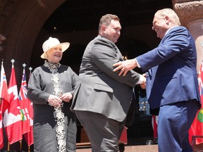 Minister of Citizenship and Multiculturalism, Michael Ford shakes hands with Premier Doug Ford as Lieutenant-Governor of Ontario Elizabeth Dowdeswell looks on, at the swearing-in ceremony at Queen’s Park in Toronto on June 24, 2022.