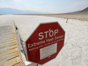 In this file photo taken June 17, 2021, a sign warns of extreme heat danger at the salt flats of Badwater Basin inside Death Valley National Park in Inyo County, Calif.