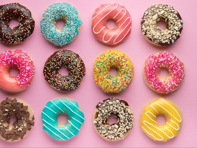 Colorful sweet background. Delicious glazed donuts on pink background.