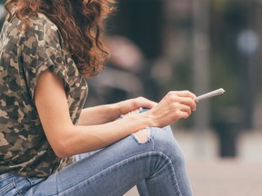 Young female holding a marijuana joint in her hand, ready to smoke. Urban weed smoking.