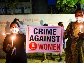 Lawyers display a placard to condemn the alleged gang-rape and murder of a low-caste teenaged woman in Uttar Pradesh state during a candlelight vigil in Ahmedabad on October 6, 2020. (Photo by SAM PANTHAKY/AFP via Getty Images)