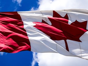 Canada flag waving on a blue sky.